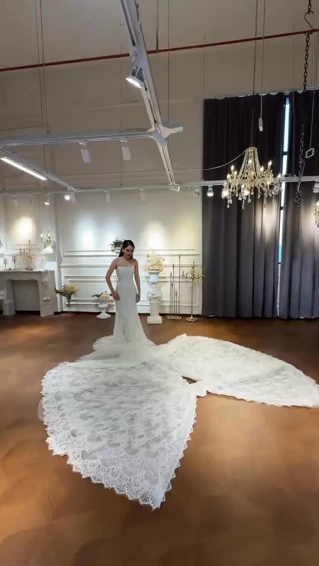 Woman wearing a white strapless mermaid wedding dress with a long lace train.