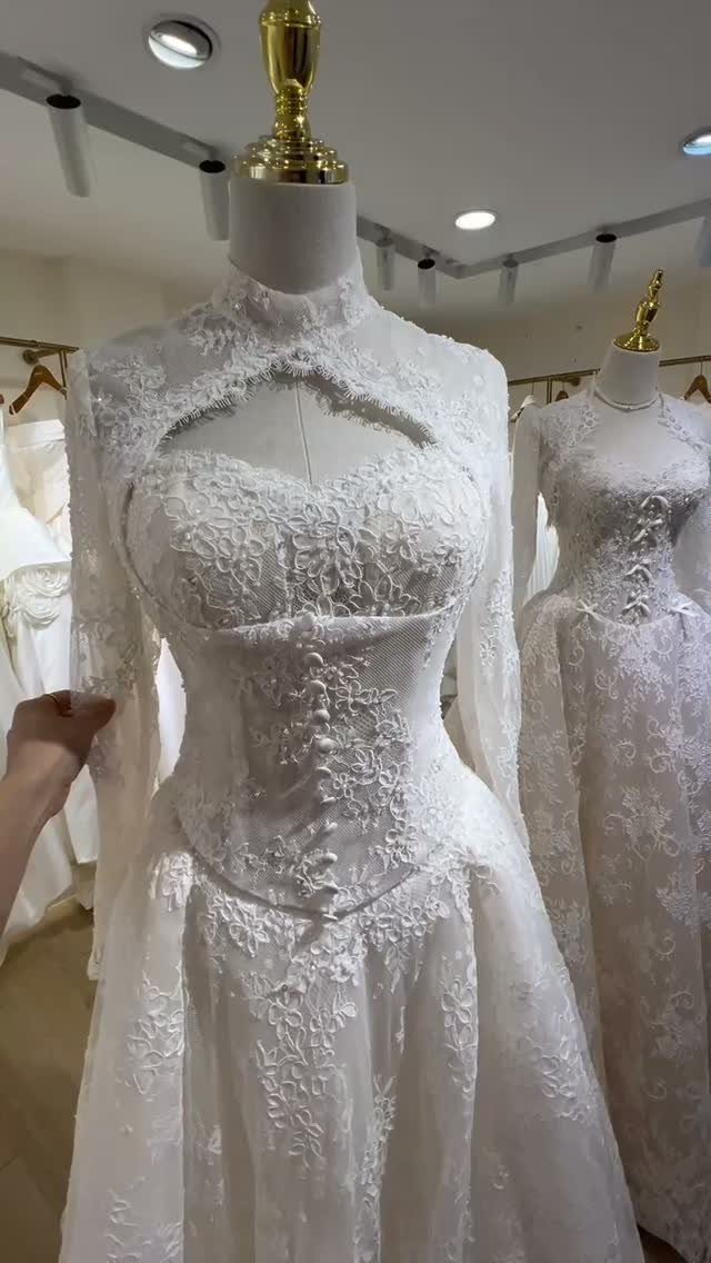 White lace wedding dress with long sleeves and a high neckline on a mannequin.
