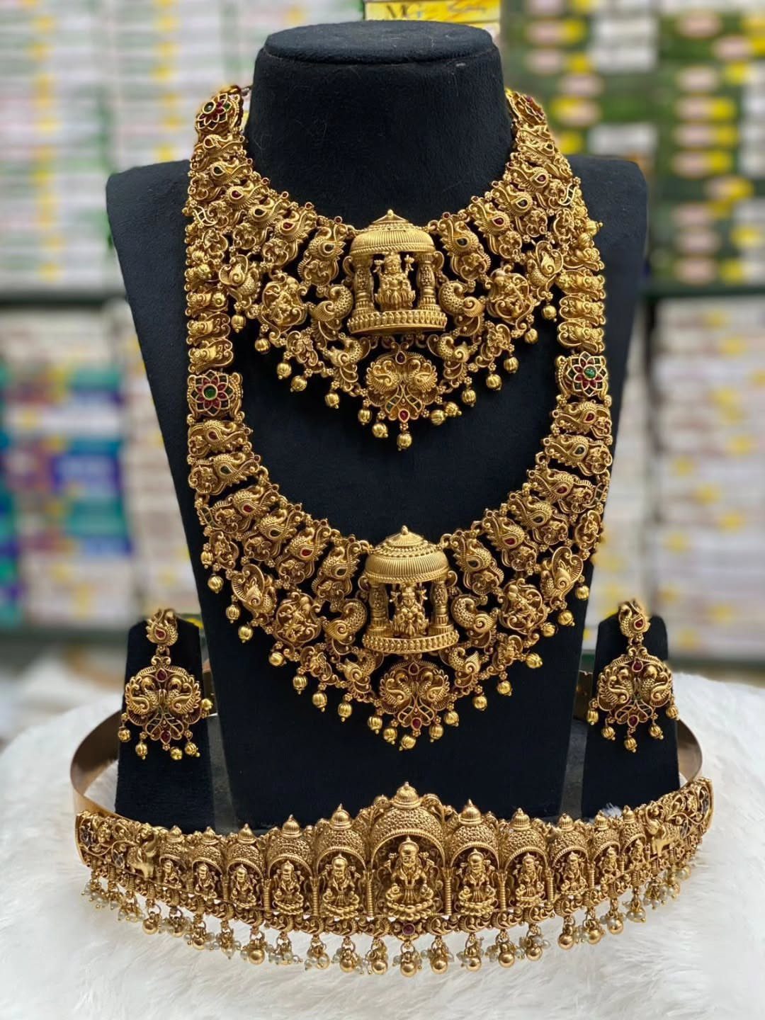 Ornate antique gold jewelry set featuring layered necklaces, earrings, and a waist belt on a black bust.