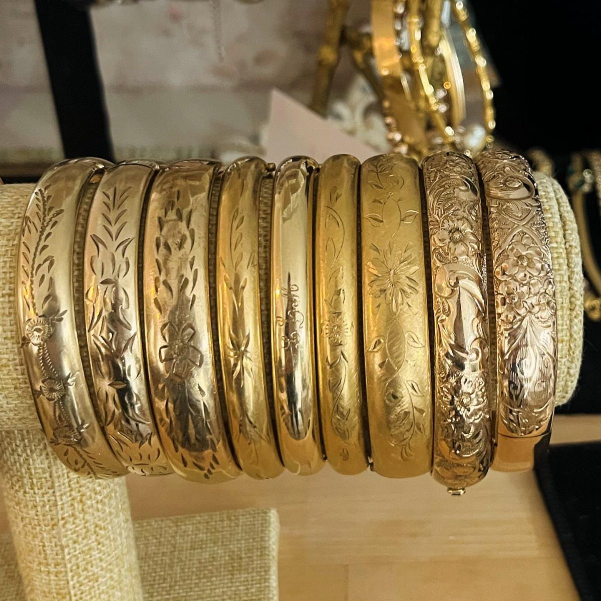 Multiple engraved antique gold bangles arranged on a jewelry display stand.