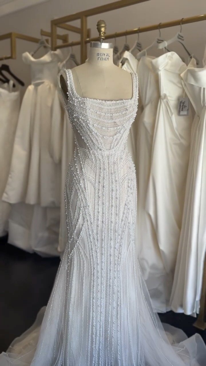 Art Deco Wedding Dress: 11 Styles From Beaded Trains to Choker Accents 1 A white wedding dress with intricate geometric beadwork displayed on a mannequin in a boutique.