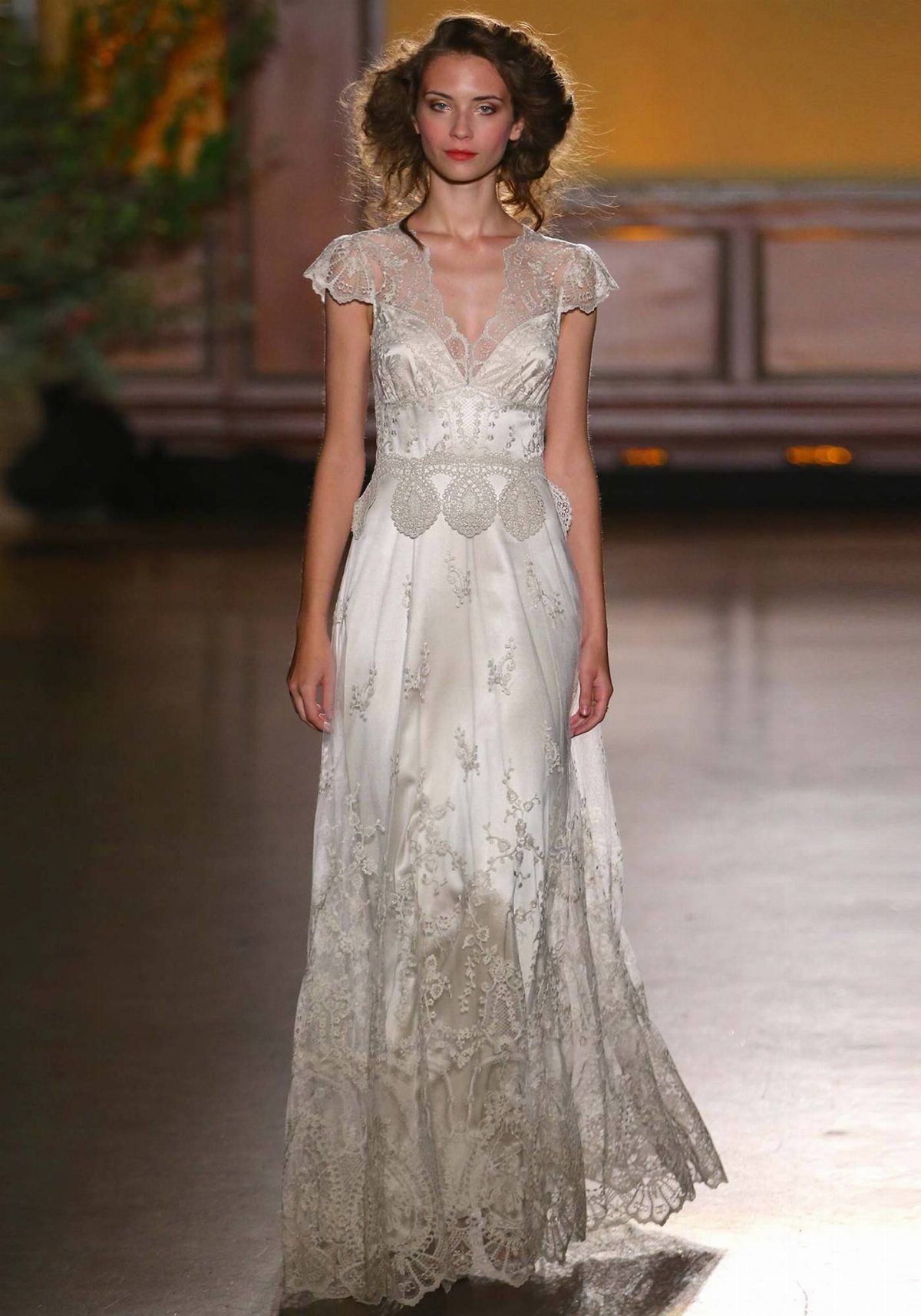 Art Deco Wedding Dress: 11 Styles From Beaded Trains to Choker Accents 5 A woman in a white embroidered wedding dress walking down a runway during a fashion show.