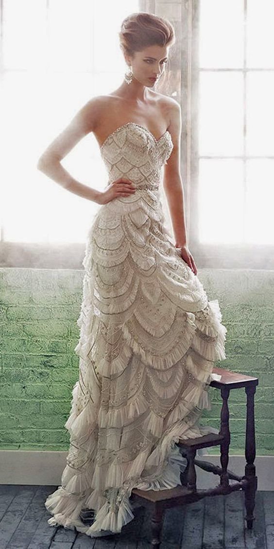Art Deco Wedding Dress: 11 Styles From Beaded Trains to Choker Accents 8 Woman wearing a tiered, scalloped lace wedding dress with intricate beadwork and ruffles.