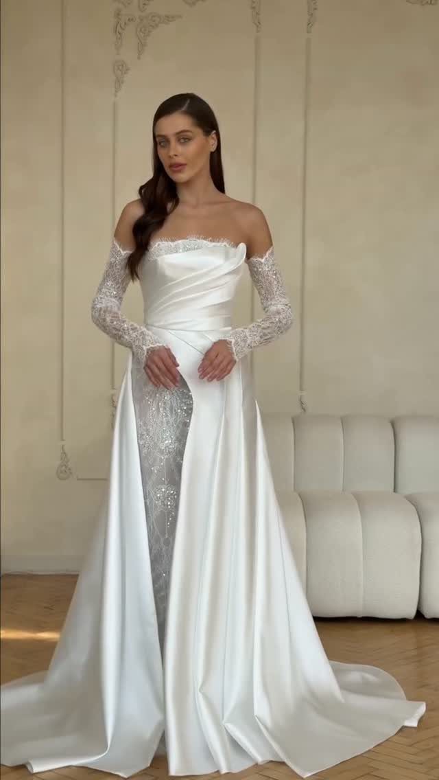 Woman wearing a white satin wedding dress with a sequined skirt and lace detachable sleeves.