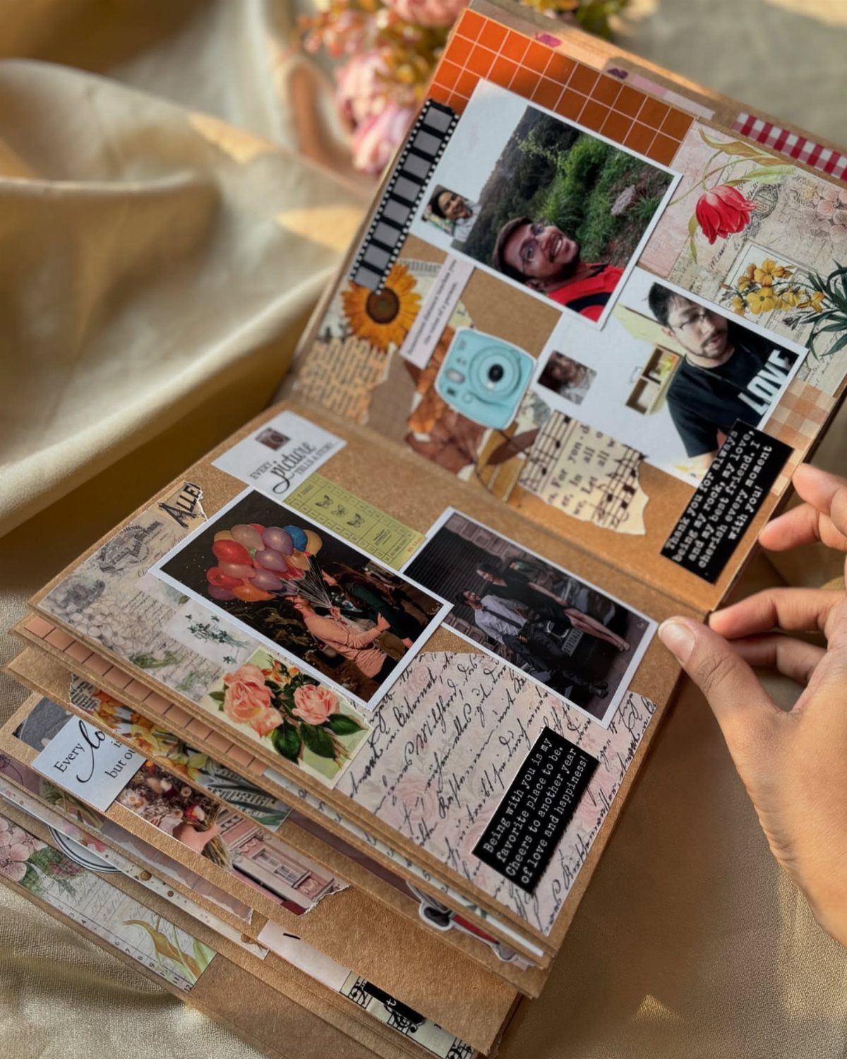 An open scrapbook filled with colorful photographs, floral decorations, and handwritten notes on textured paper.