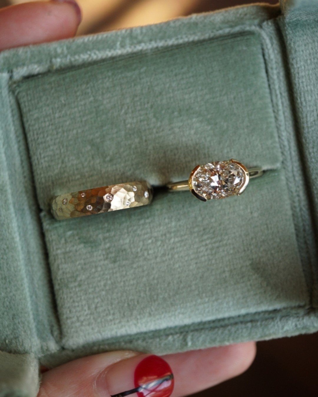 Two gold rings, one with a diamond solitaire and one hammered band, in a green velvet box.