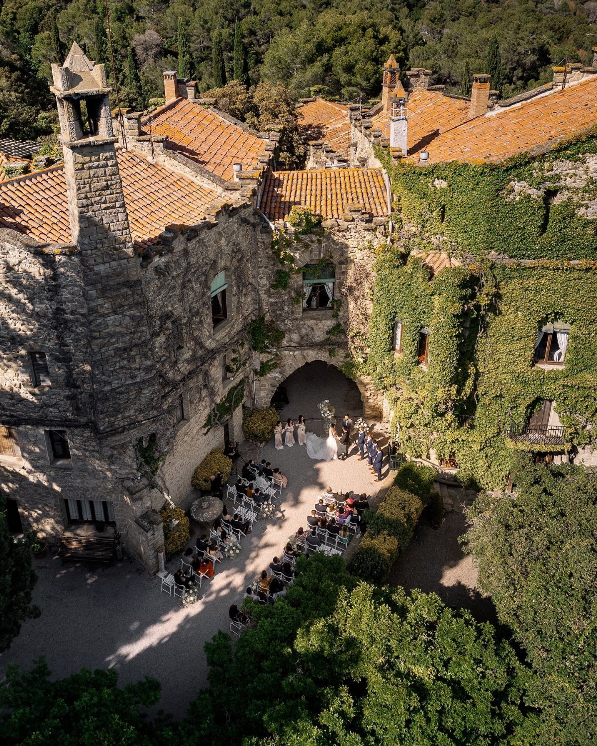 An aerial view of an outdoor wedding ceremony set in a stone courtyard of a historic estate.