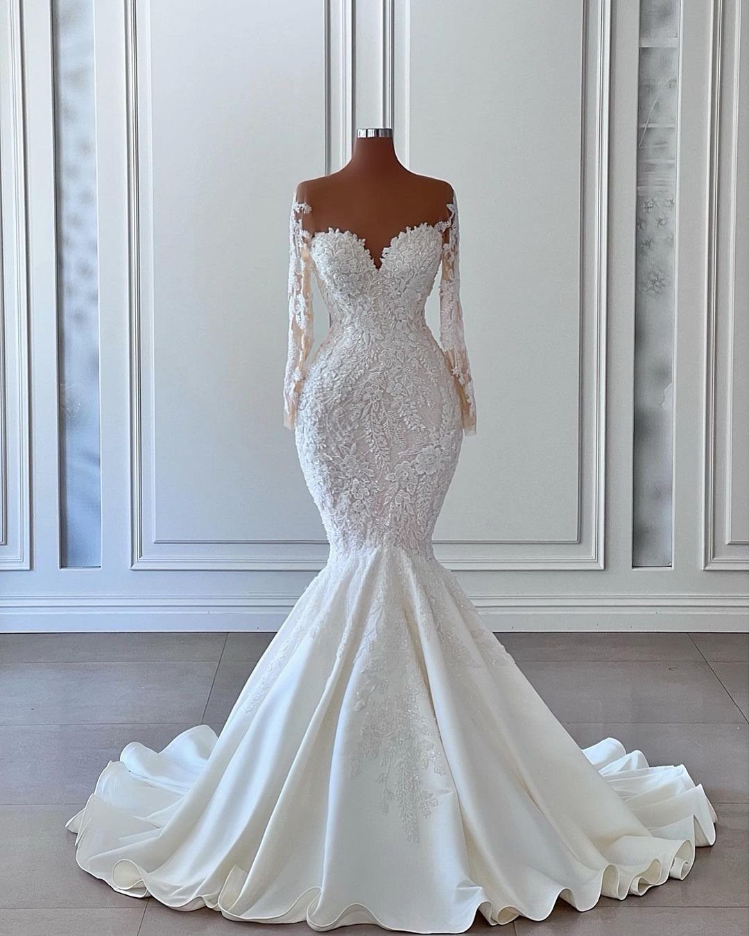 An ivory lace mermaid wedding dress with long sleeves displayed on a mannequin.