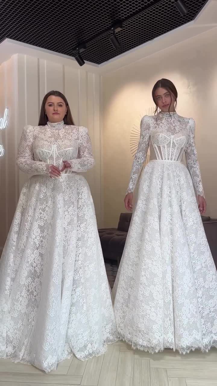 Two women posing in white lace wedding dresses with different bodice designs.