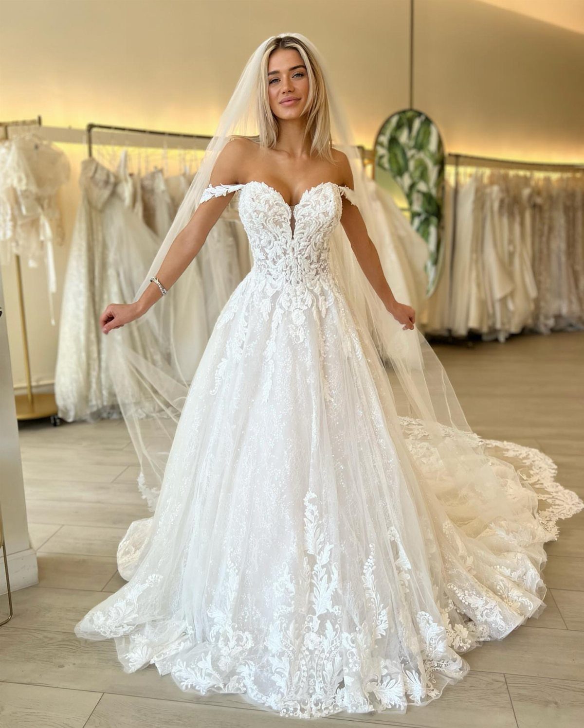A woman in a white lace wedding dress with a sweetheart neckline and long veil.