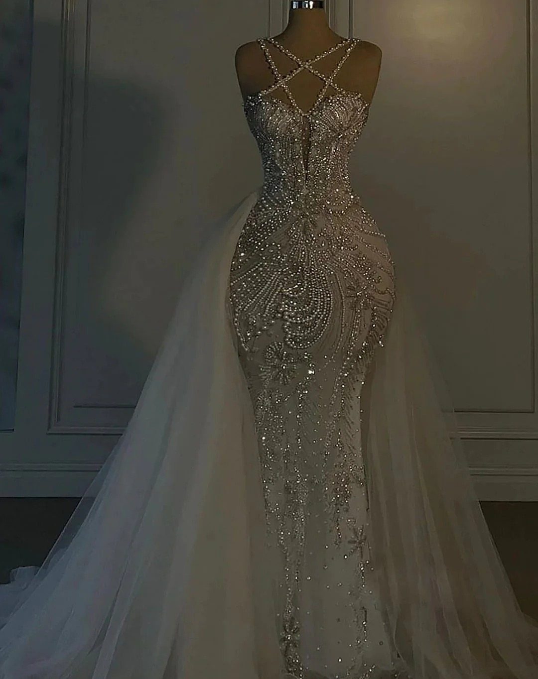 A mermaid silhouette wedding dress heavily embellished with sparkling rhinestones and crystals on a mannequin.