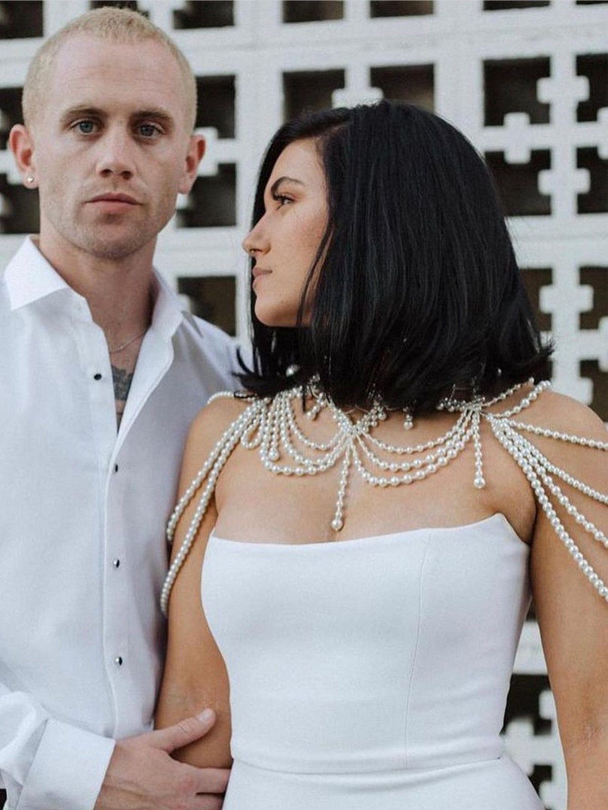 A woman wearing a white pearl beaded shoulder drape over a strapless wedding dress.