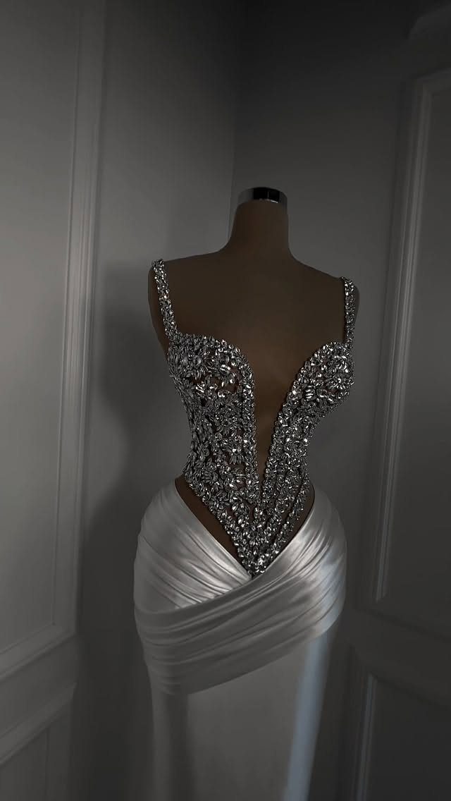 A white satin wedding dress with a sparkling crystal-encrusted corset bodice on a mannequin.