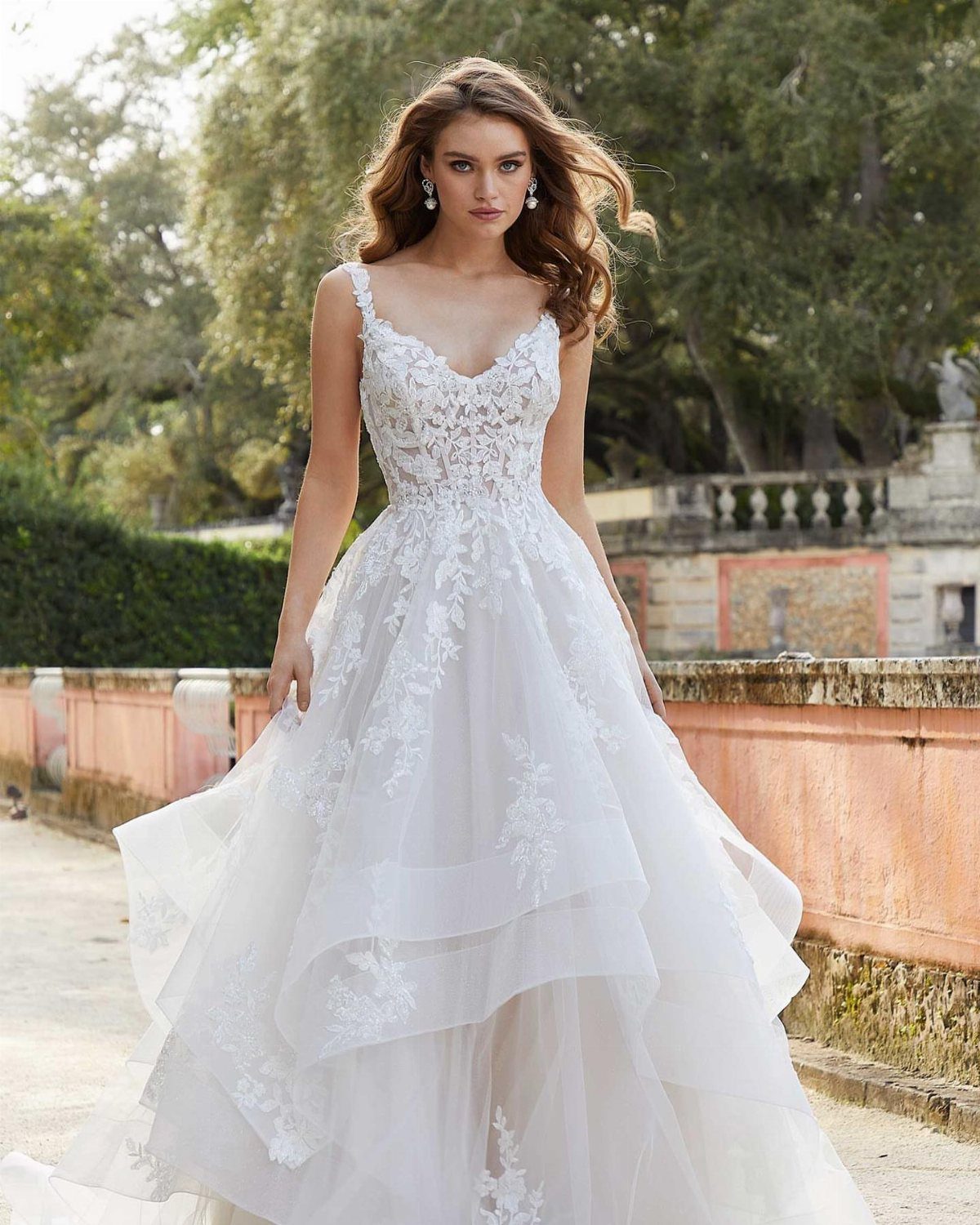 A woman wearing a white lace sweetheart neckline A-line wedding dress standing in a garden.