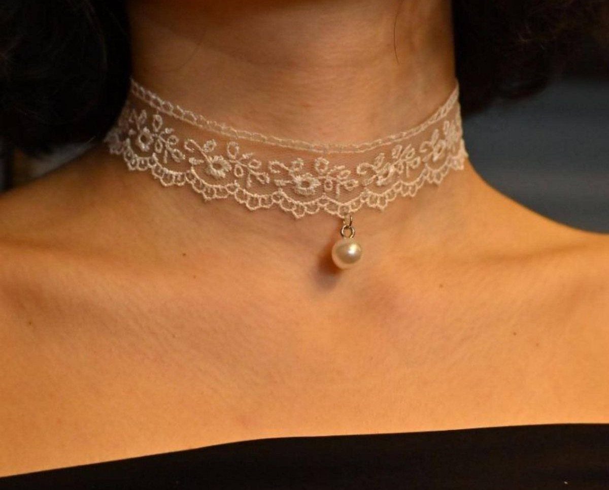 White lace choker with a pearl pendant worn on a person's neck