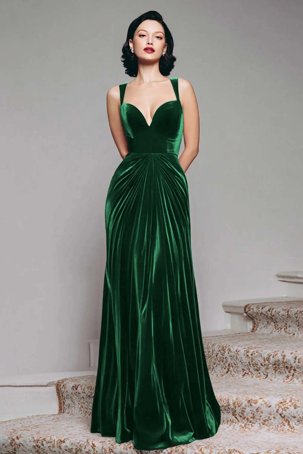 Woman in an emerald green velvet V-neck maxi dress standing on carpeted stairs.