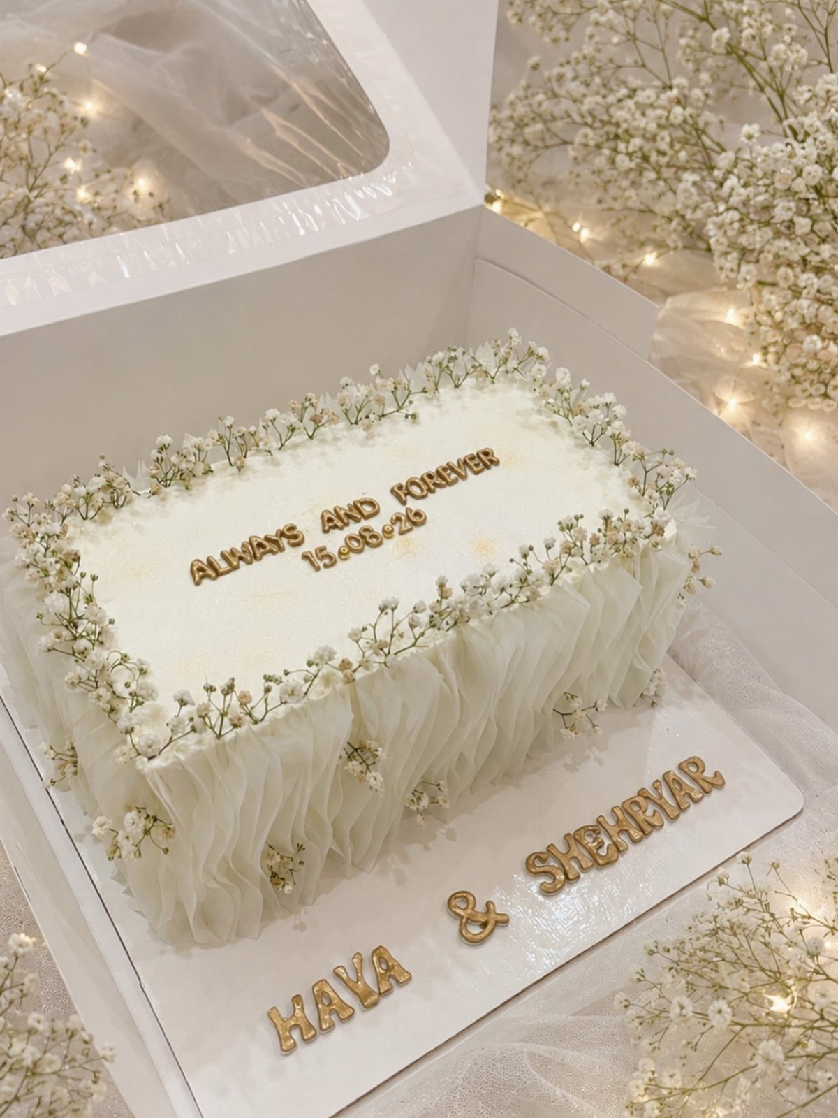 Wedding Cakes for 100 Guests: 6 Designs That Actually Work 4 Rectangular white wedding cake decorated with baby's breath flowers and gold lettering in a white box.