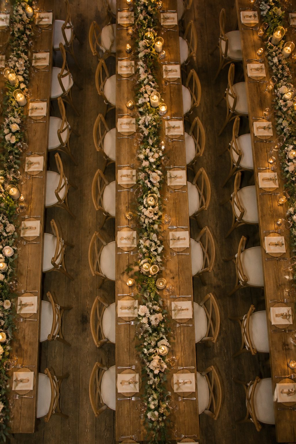 Reception tables featuring centerpieces and personalized settings with greenery.