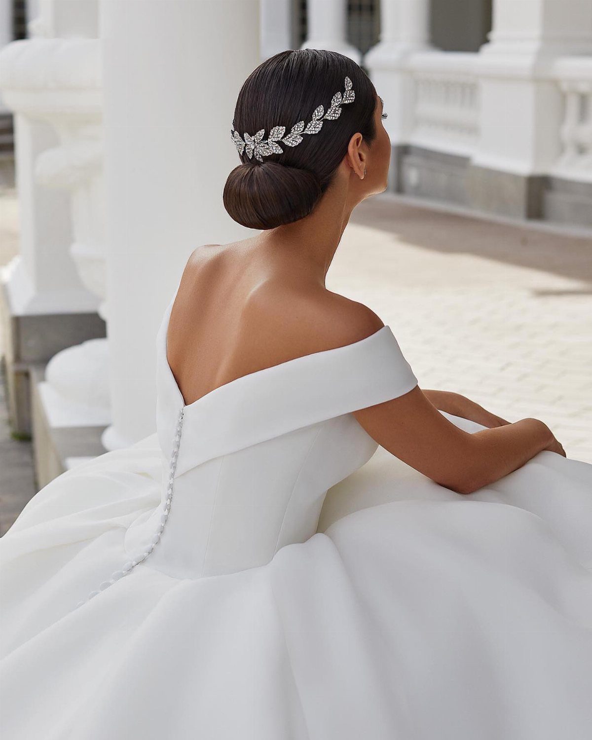 Woman in an off-the-shoulder white wedding dress with a decorative headband in her hair.