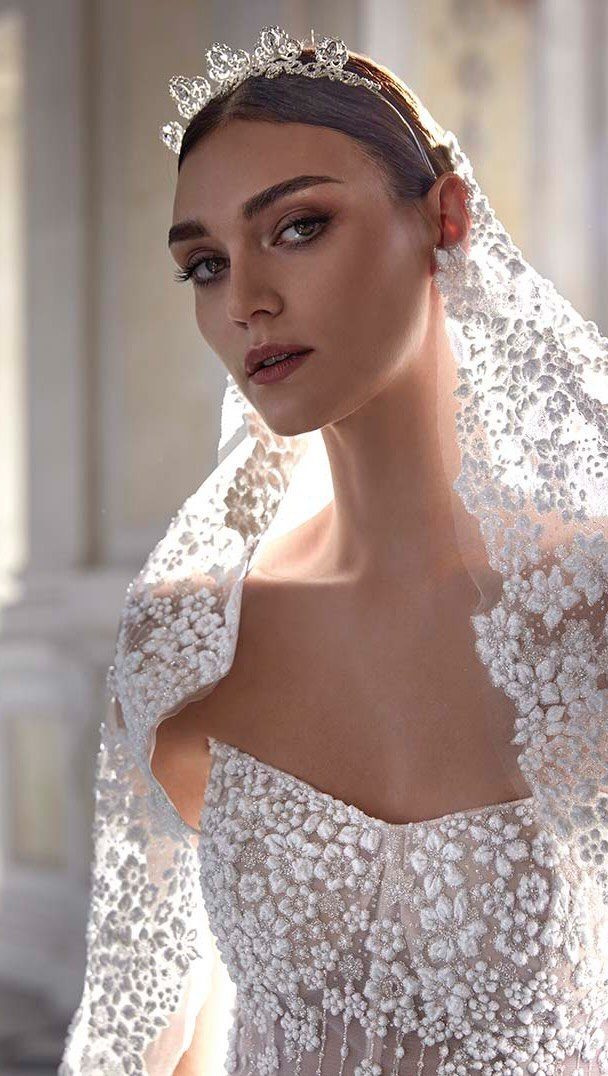 A woman wearing a white lace mantilla veil and a sparkling tiara.