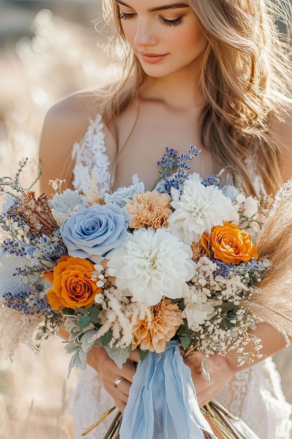 A bride holding a large bouquet of blue, white, and orange flowers with blue ribbons.