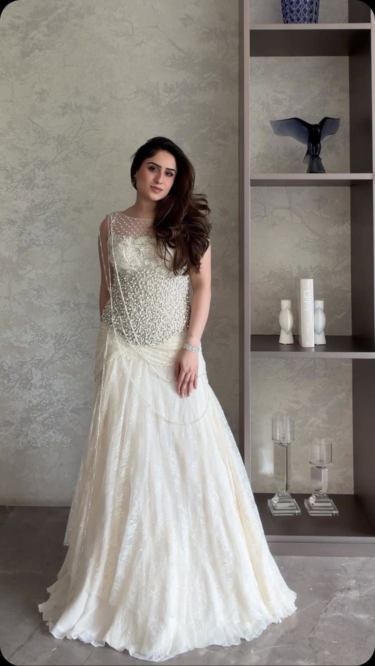 A woman wearing a white wedding dress with a heavily pearl-embellished bodice and full skirt.