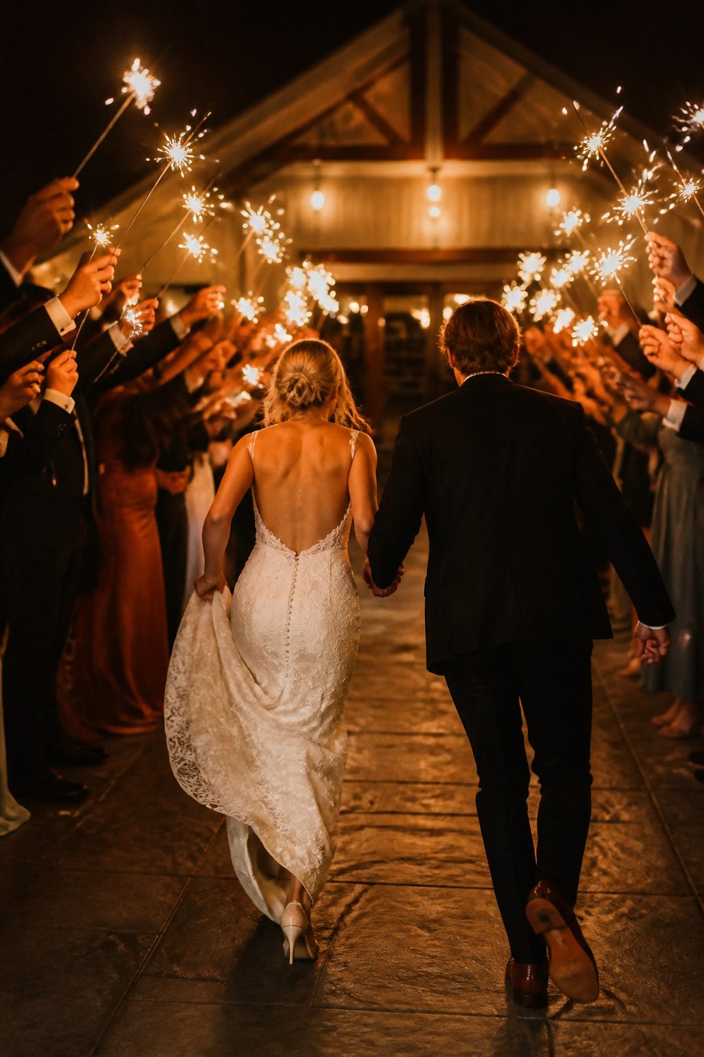 Couple exiting reception with sparklers held by guests.