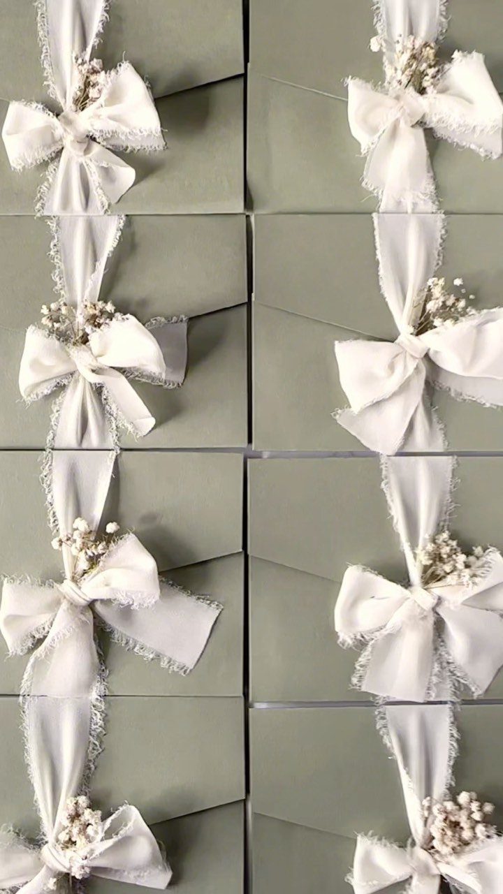 Wedding Invitations with Ribbon: 5 Ideas That Look Handmade 2 Sage green envelopes decorated with white silk ribbon bows and small sprigs of dried baby's breath.
