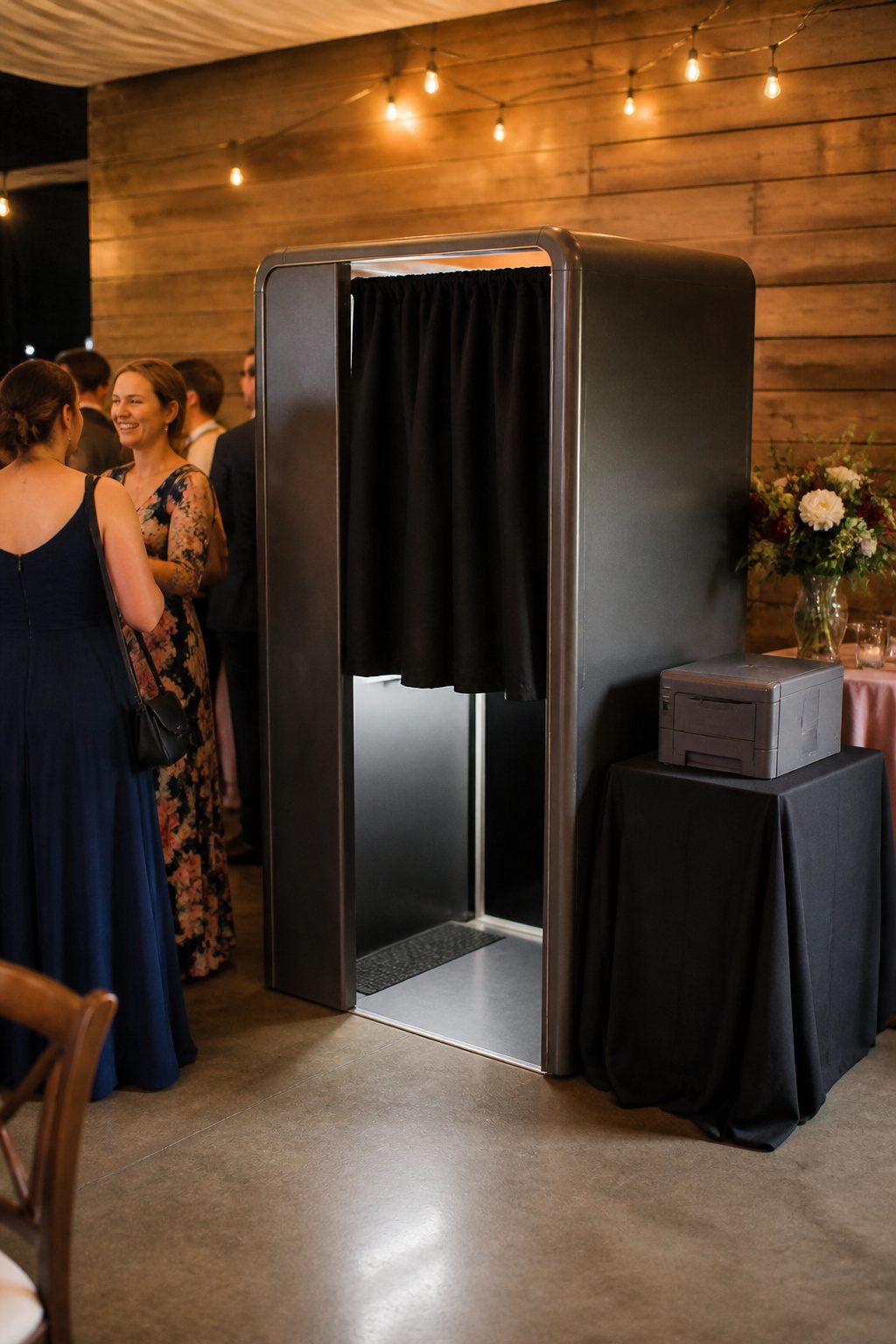 A traditional enclosed photo booth with a black curtain and retro design.