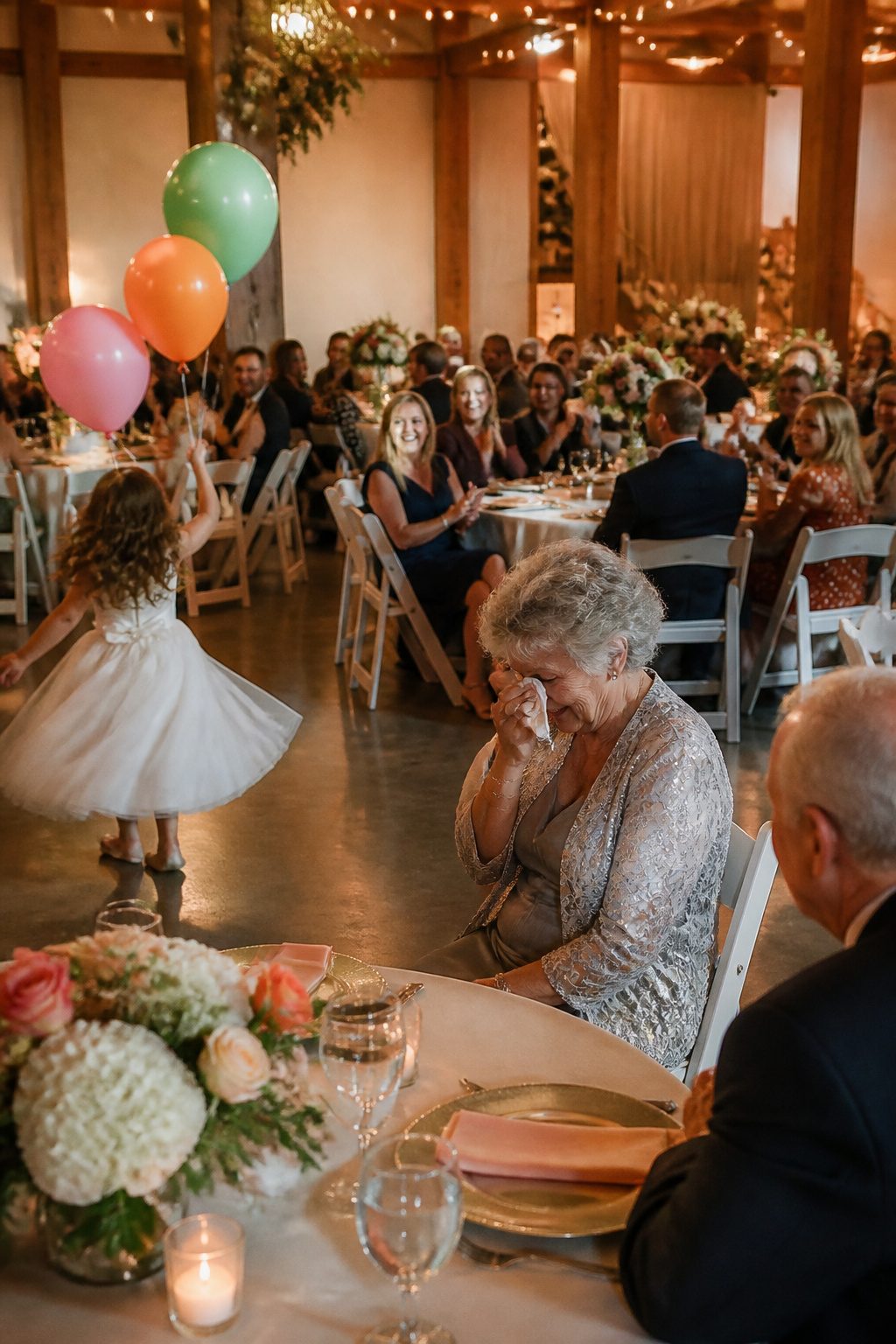A lively reception with guests laughing and a child chasing balloons.