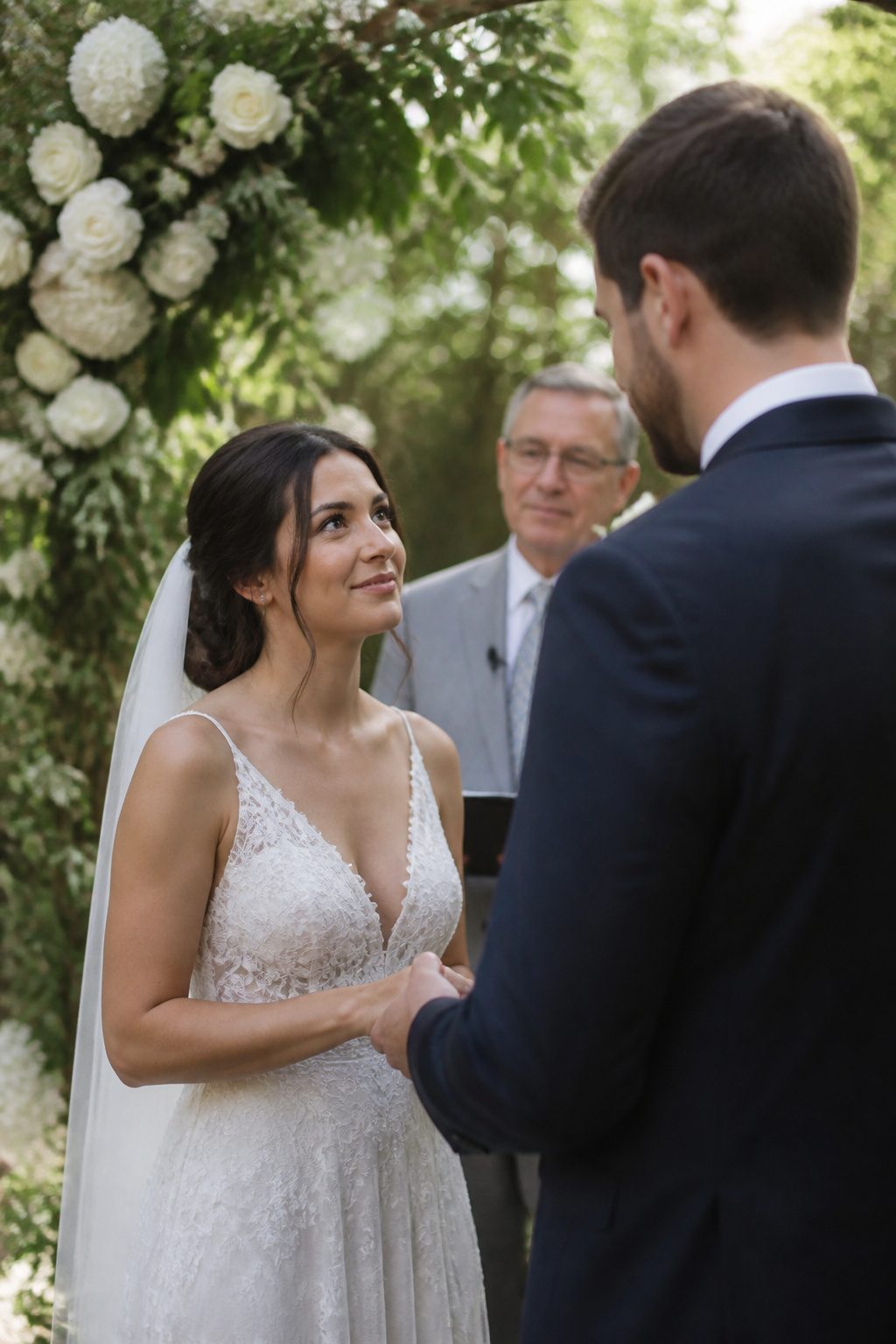A couple exchanging vows at an outdoor ceremony with greenery in the background.