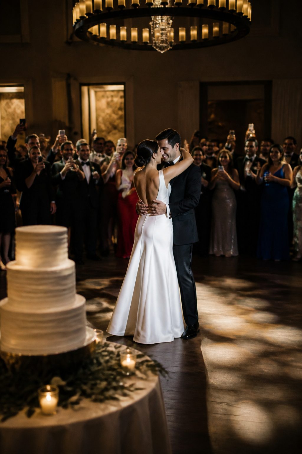A couple sharing their first dance at a lively reception with guests celebrating.
