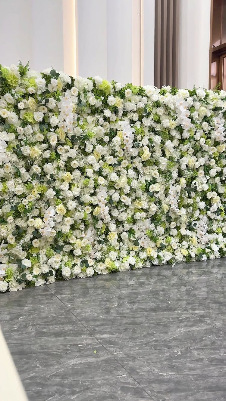 A large wall installation made of white and cream flowers with green foliage.